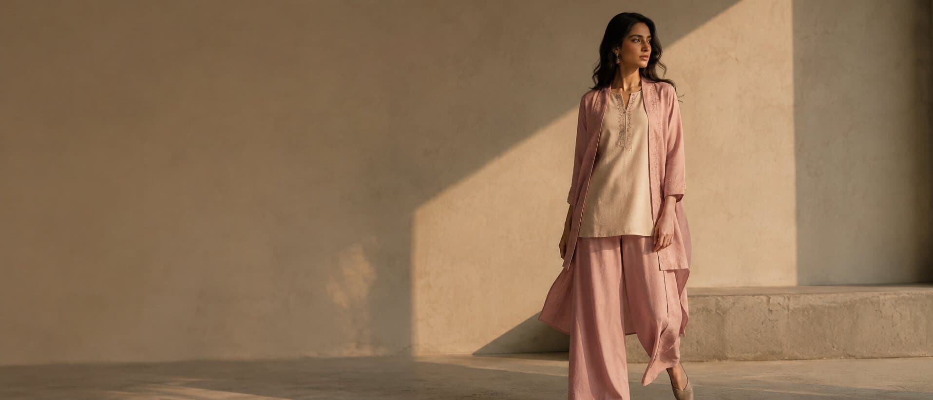 Model wearing a soft pink co-ord set in a sunlit minimalist courtyard